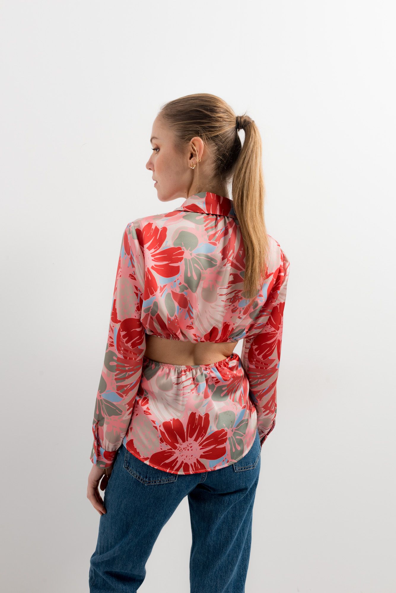 Mujer luciendo camisa blanca con estampado artístico y aberturas en hombros.