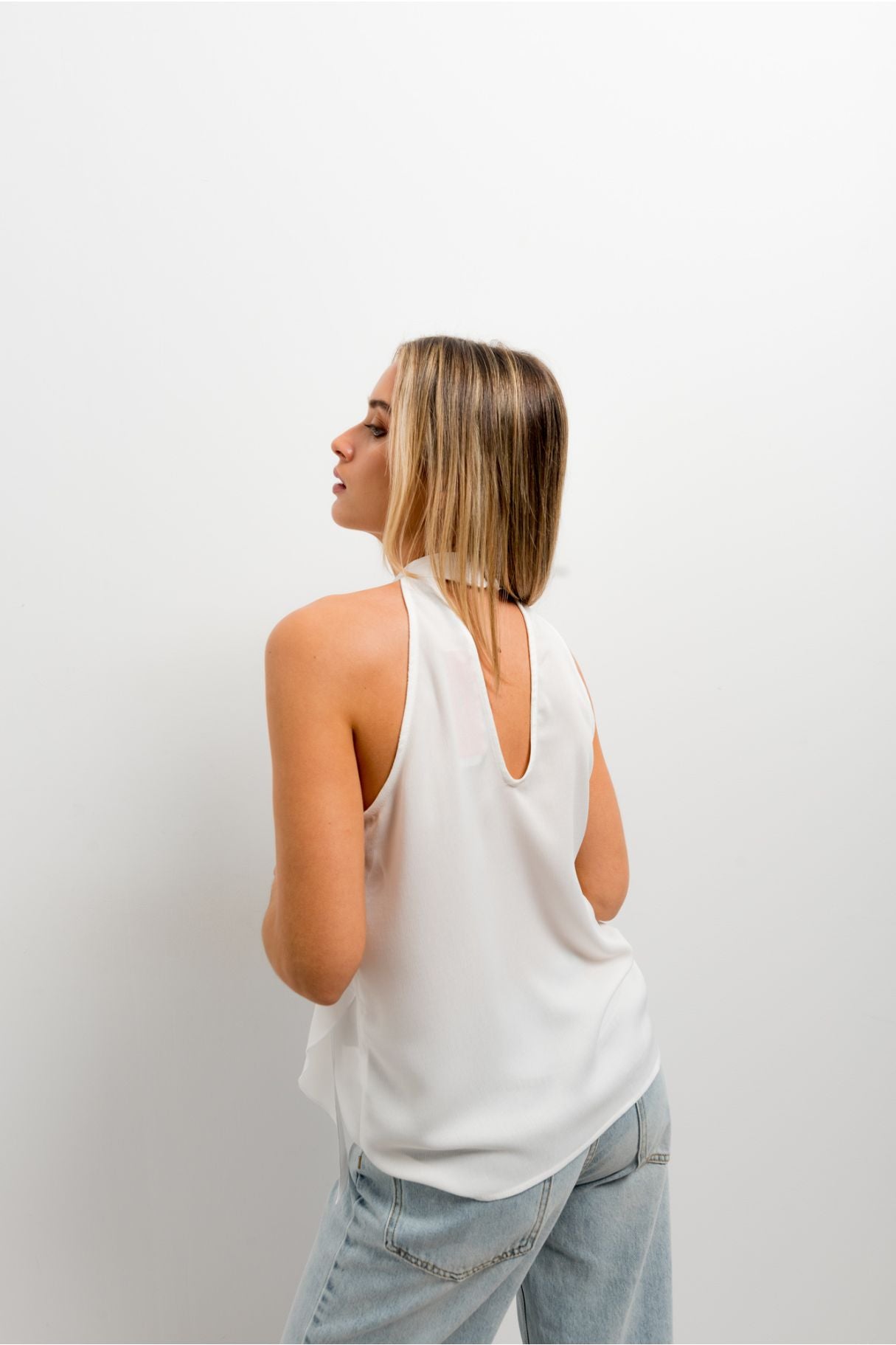 Blusa de fiesta para mujer con cuello halter y diseño texturizado de volantes en cascada de color crudo.