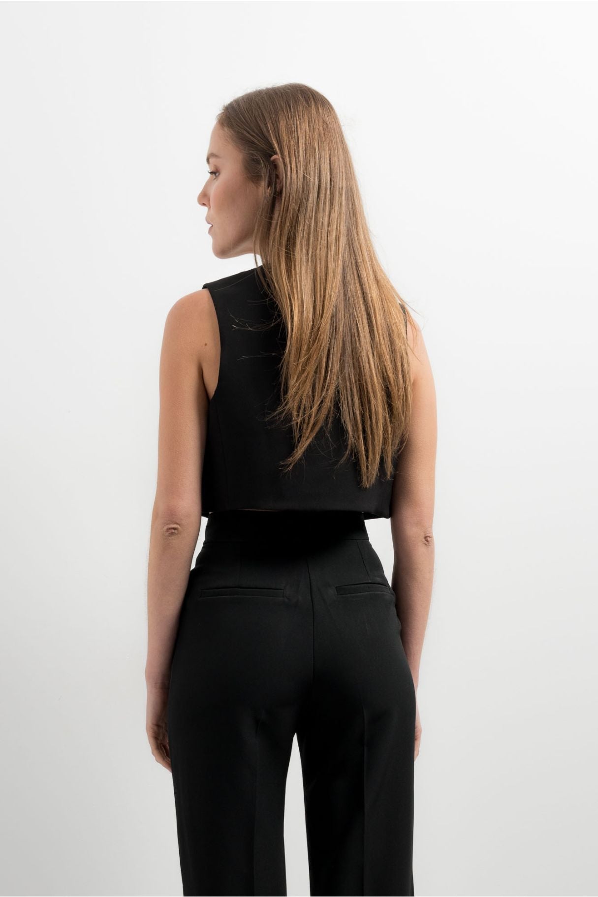 Chaleco sastre corto para mujer en color negro, de corte ajustado al cuerpo con escote en V y botones delanteros.