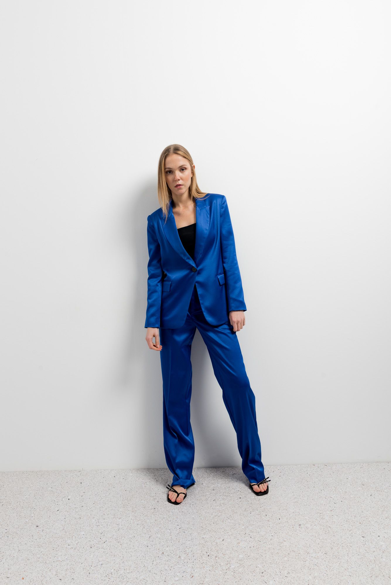 Pantalón fluido de satén azul con brillo sedoso y corte recto.