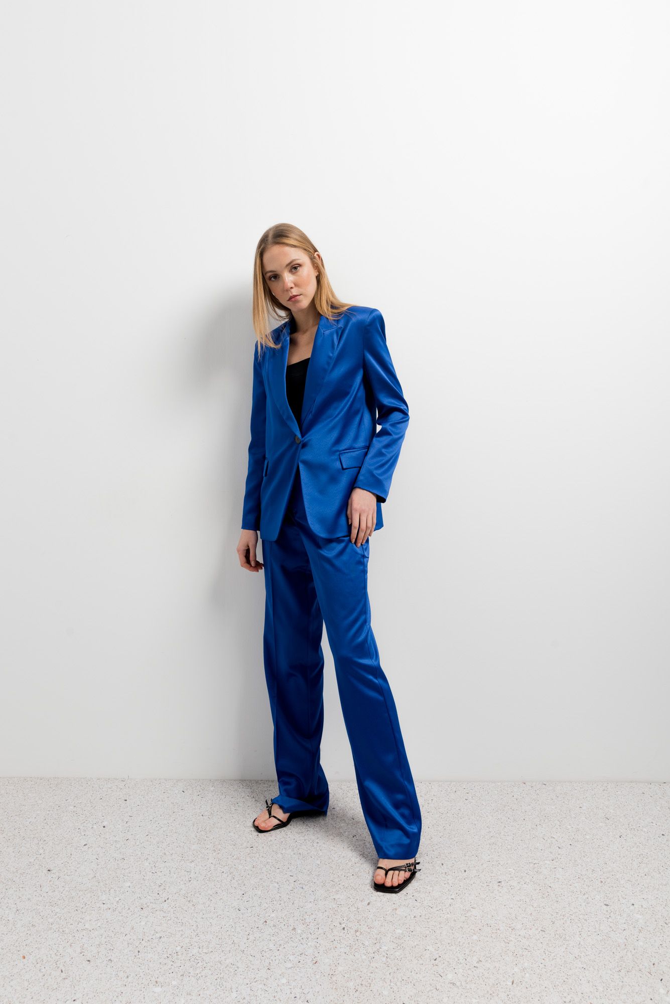 Pantalón fluido de satén azul con brillo sedoso y corte recto.