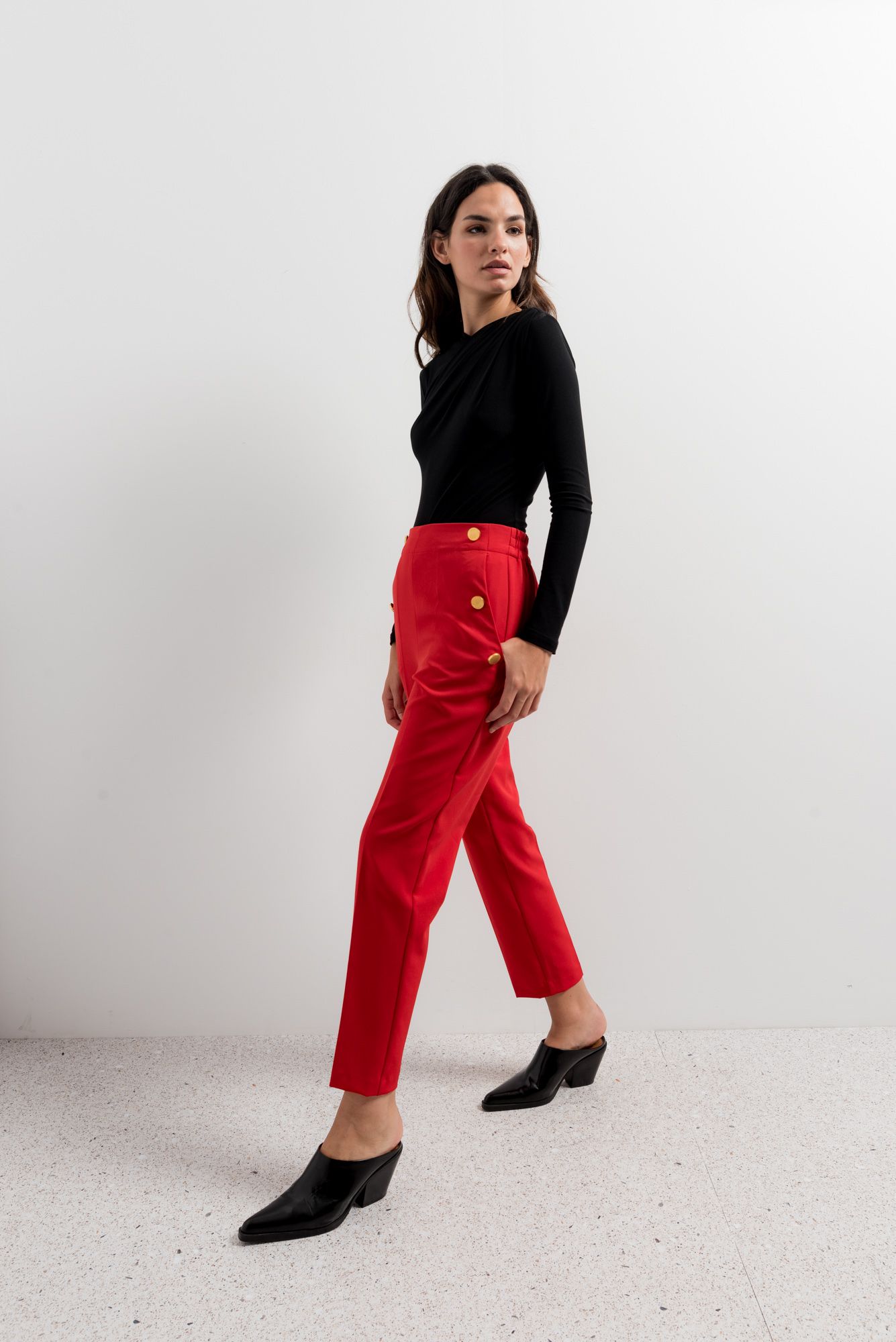 Pantalón rojo de talle alto con fila de botones dorados decorativos.