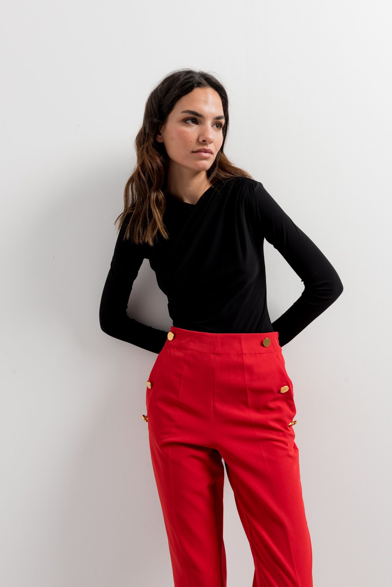 Pantalón rojo de talle alto con fila de botones dorados decorativos.