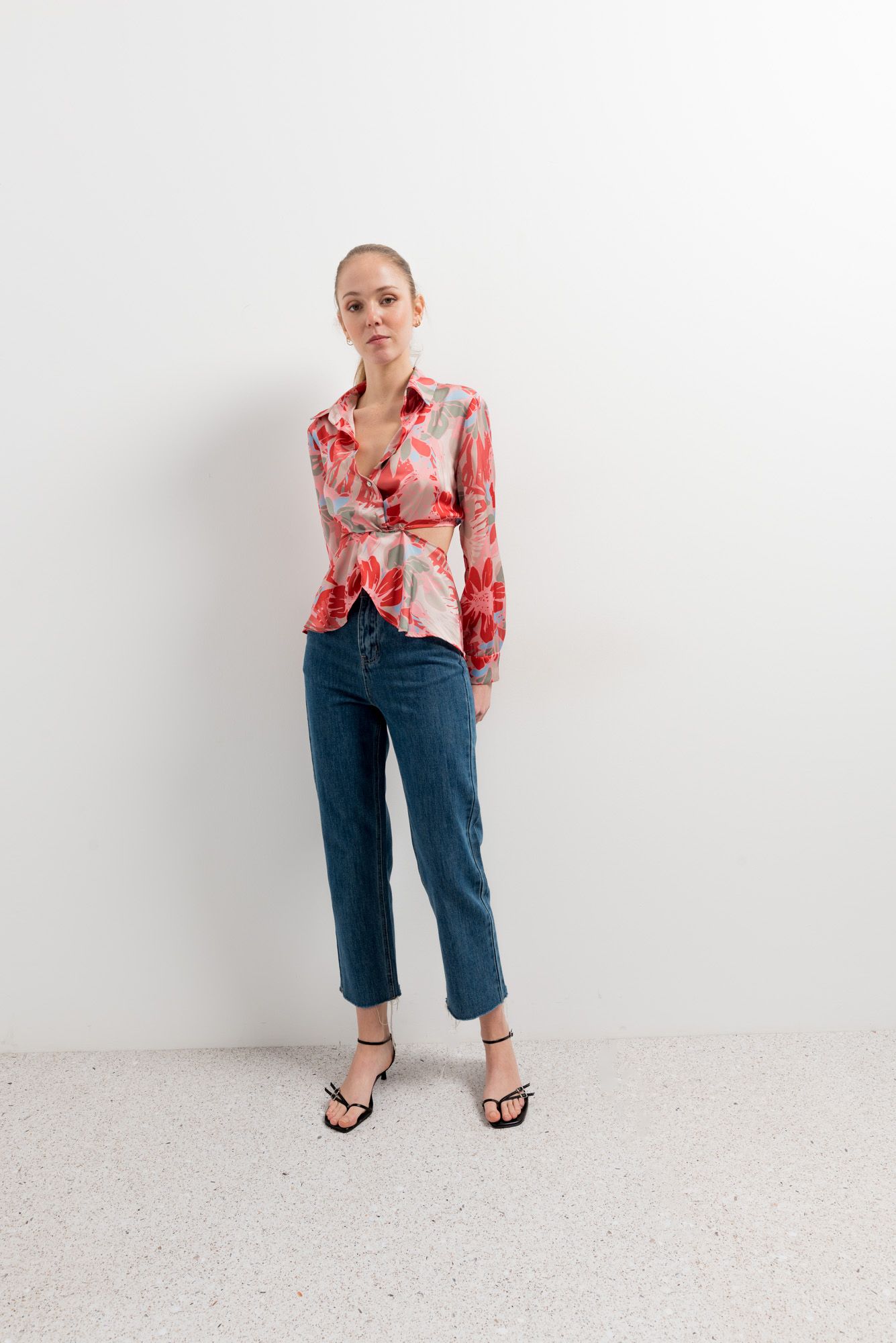 Mujer luciendo camisa blanca con estampado artístico y aberturas en hombros.