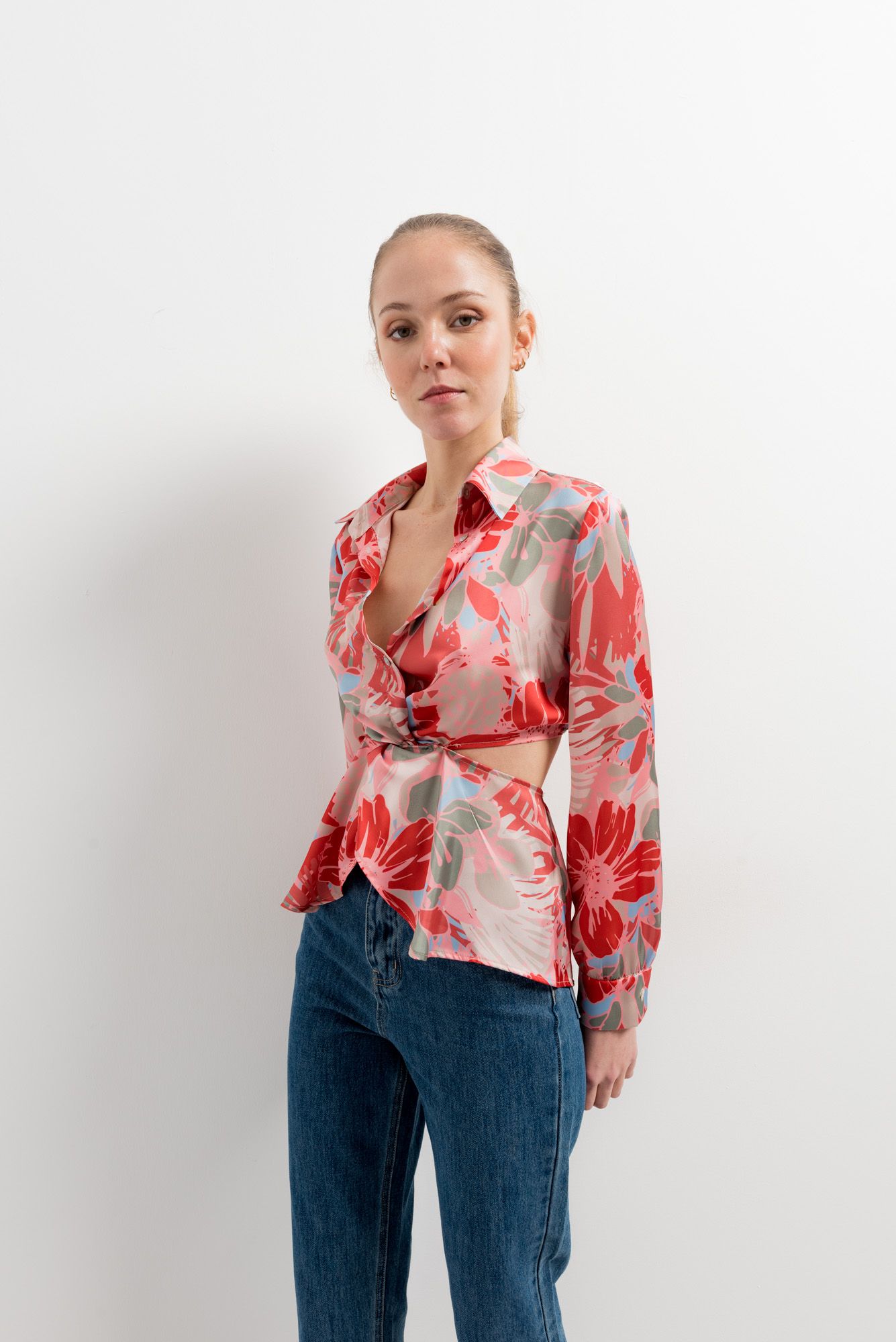 Mujer luciendo camisa blanca con estampado artístico y aberturas en hombros.