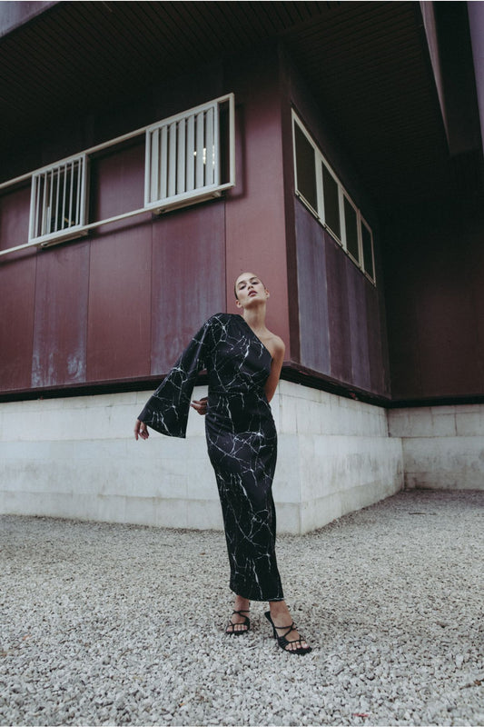 Vestido midi elegante para mujer en color negro con corte asimétrico de un solo hombro y silueta ajustada elástica.