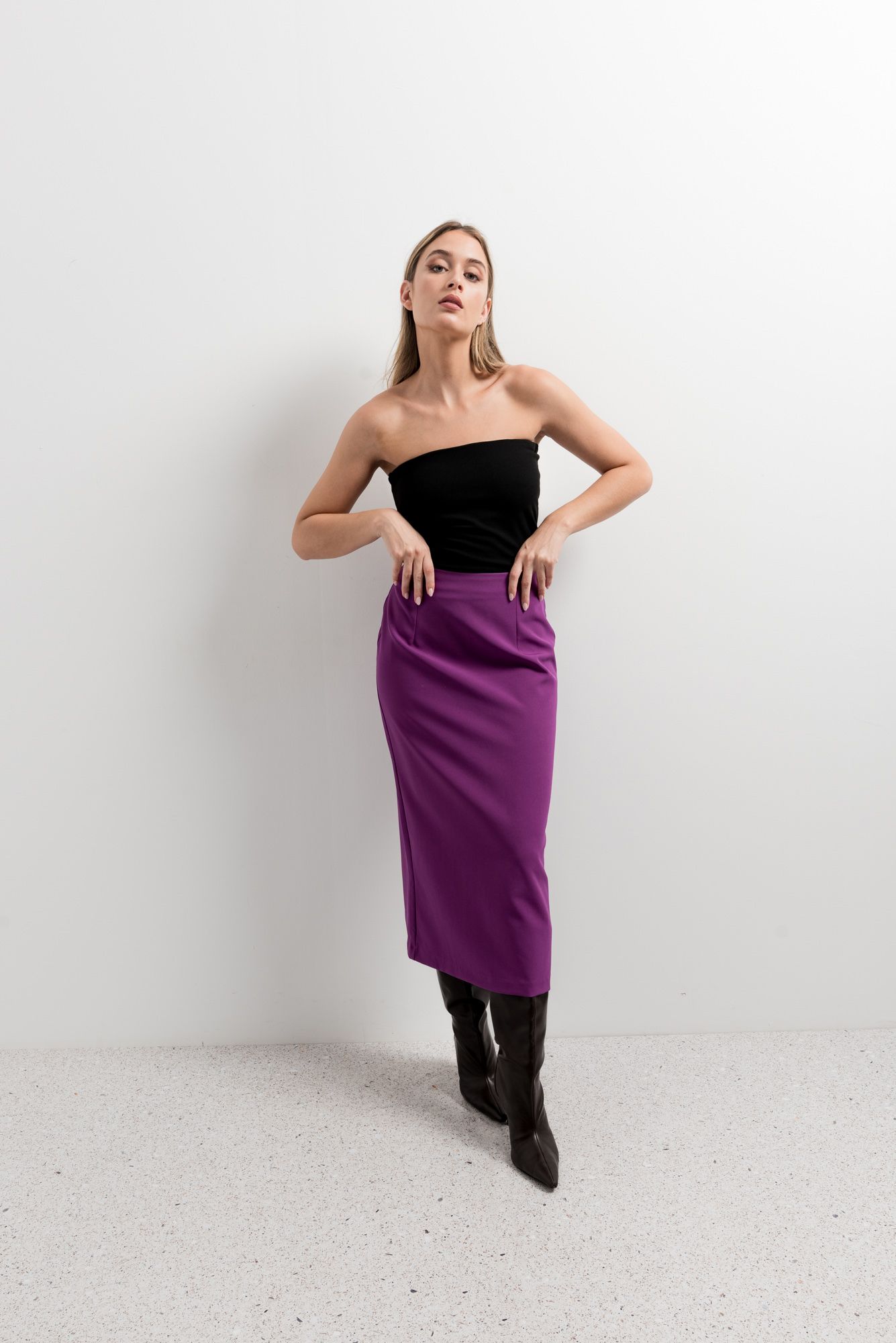 Vista trasera de falda midi morada con detalle de abertura en el bajo.