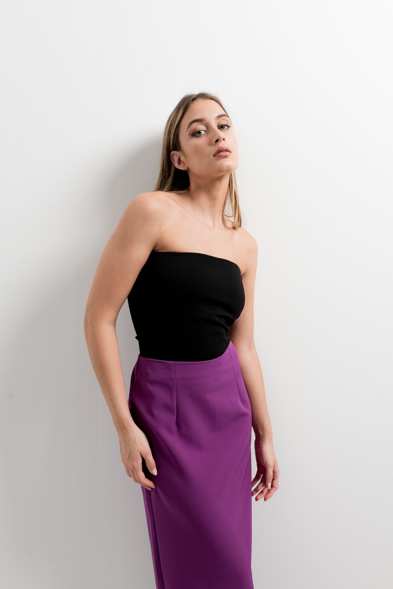 Vista trasera de falda midi morada con detalle de abertura en el bajo.