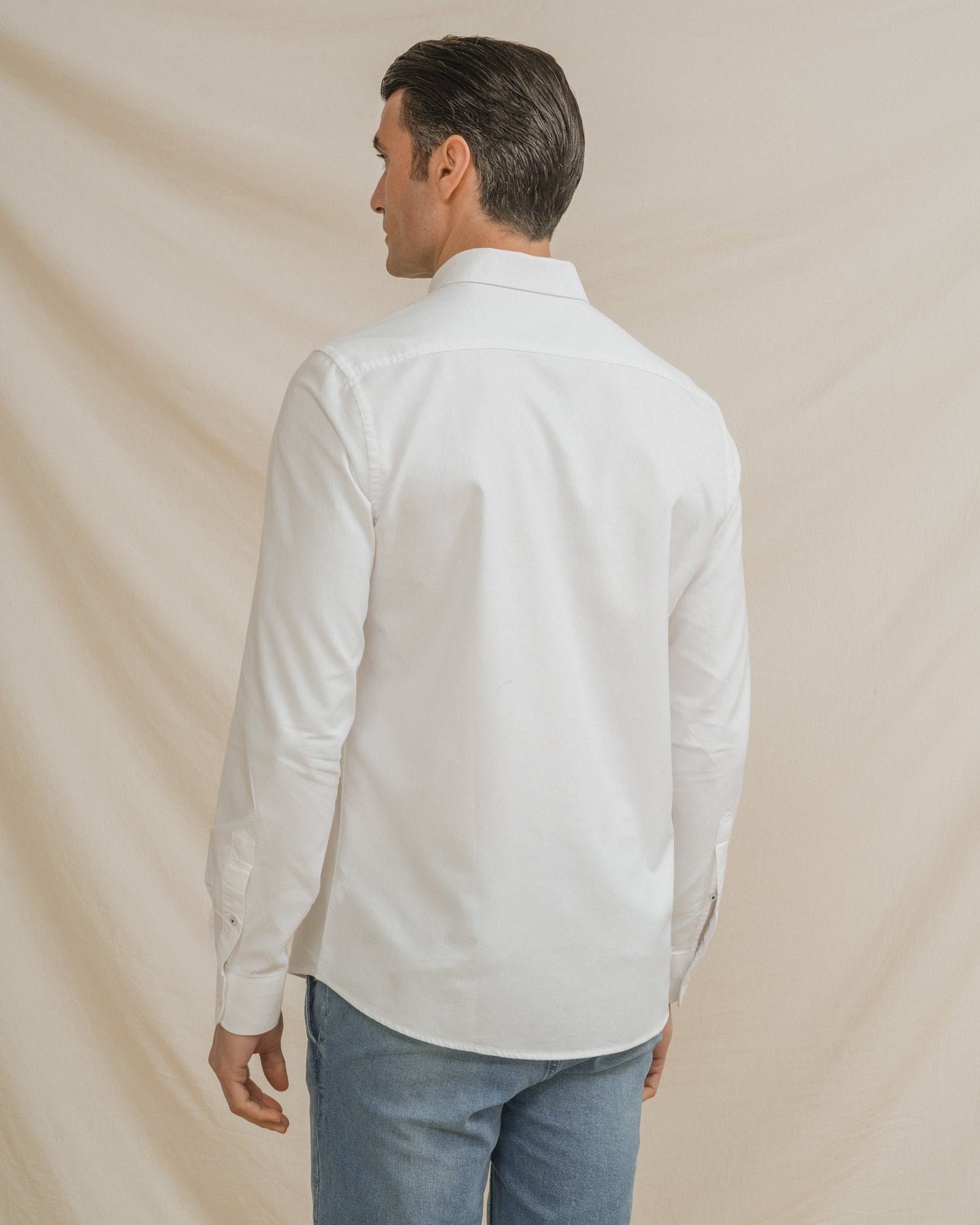 Camisa Oxford blanca de hombre con cuello botonado y detalle de logo en el pecho.