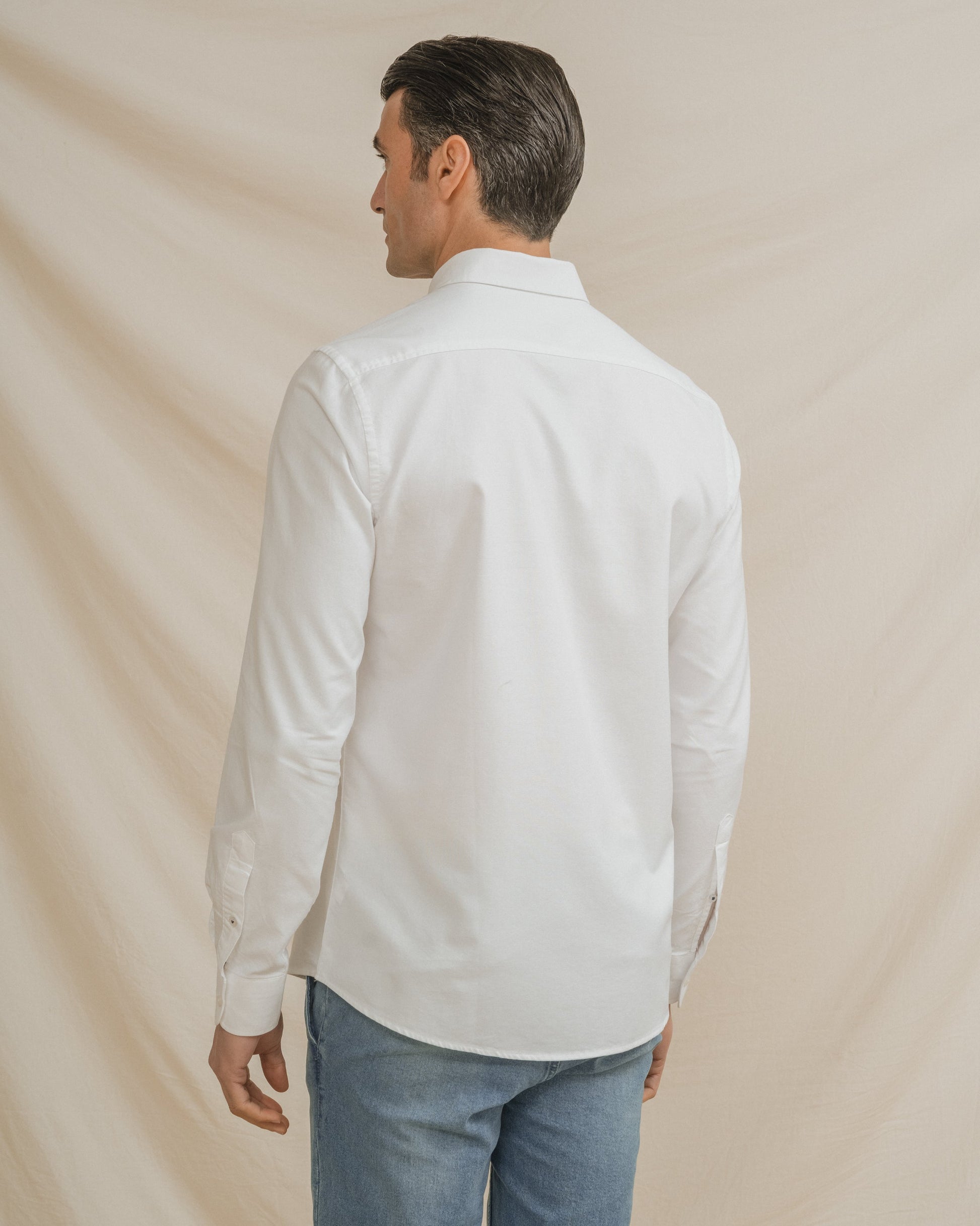 Camisa Oxford blanca de hombre con cuello botonado y detalle de logo en el pecho.