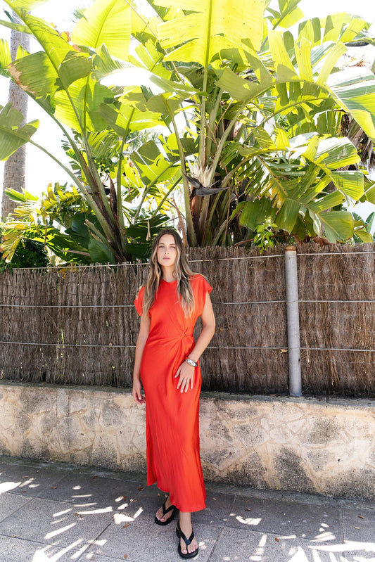 Vestido midi verde esmeralda con nudo en el delantero. Frunces que estilizan y manga corta. Cierre de cremallera en espalda.