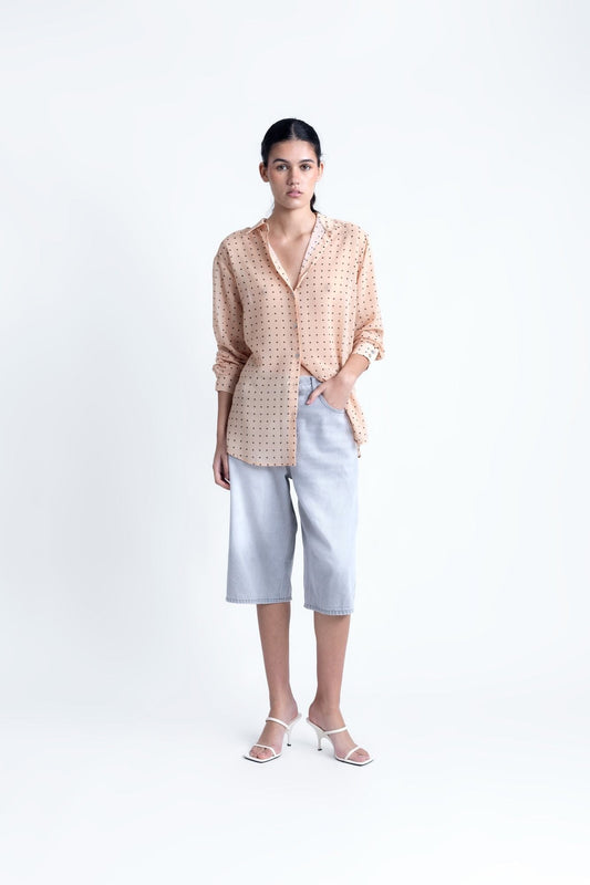 Blusa semitransparente para mujer en color beige con estampado clásico de lunares, botones frontales y mangas largas.