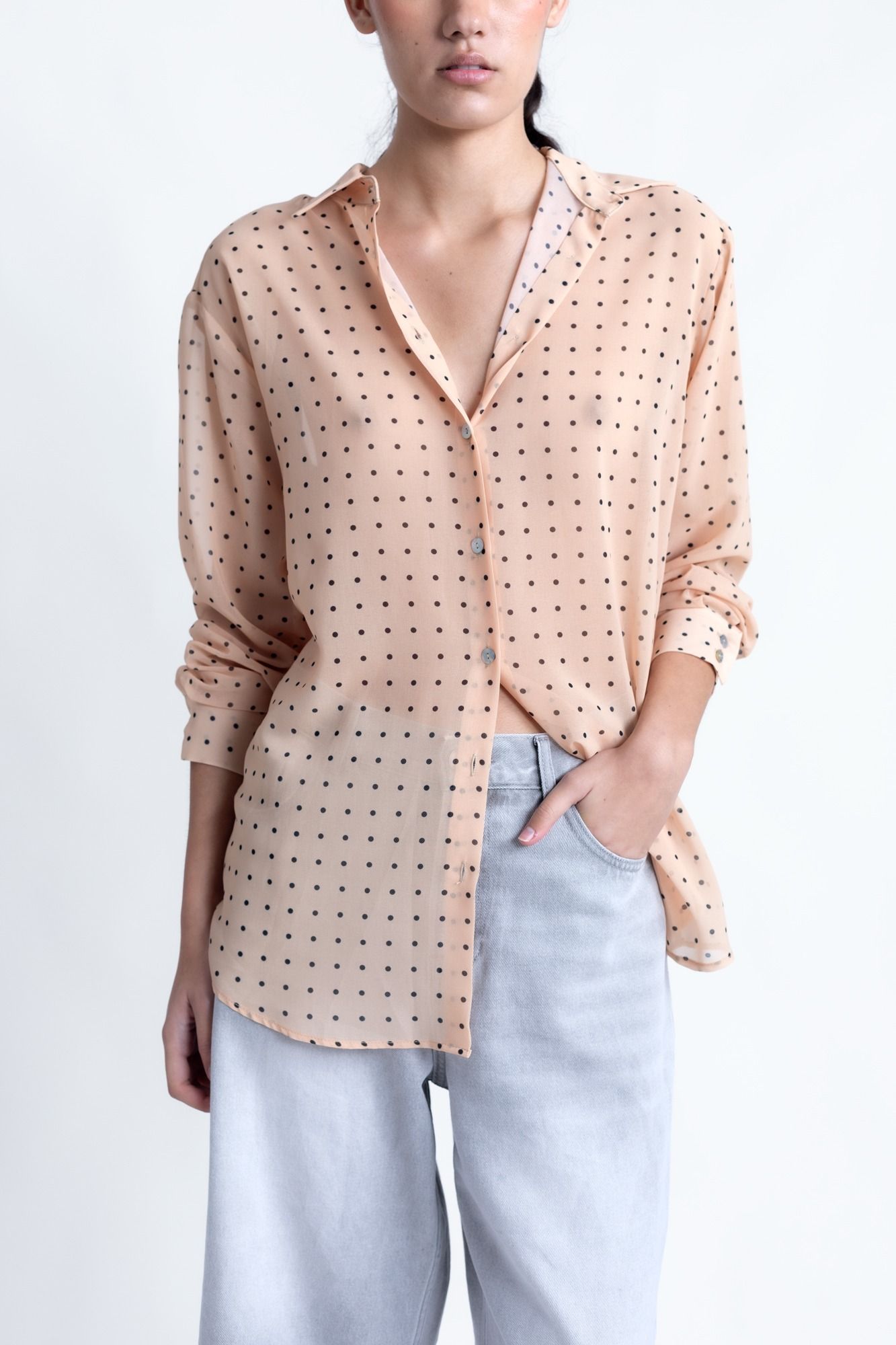 Blusa semitransparente para mujer en color beige con estampado clásico de lunares, botones frontales y mangas largas.