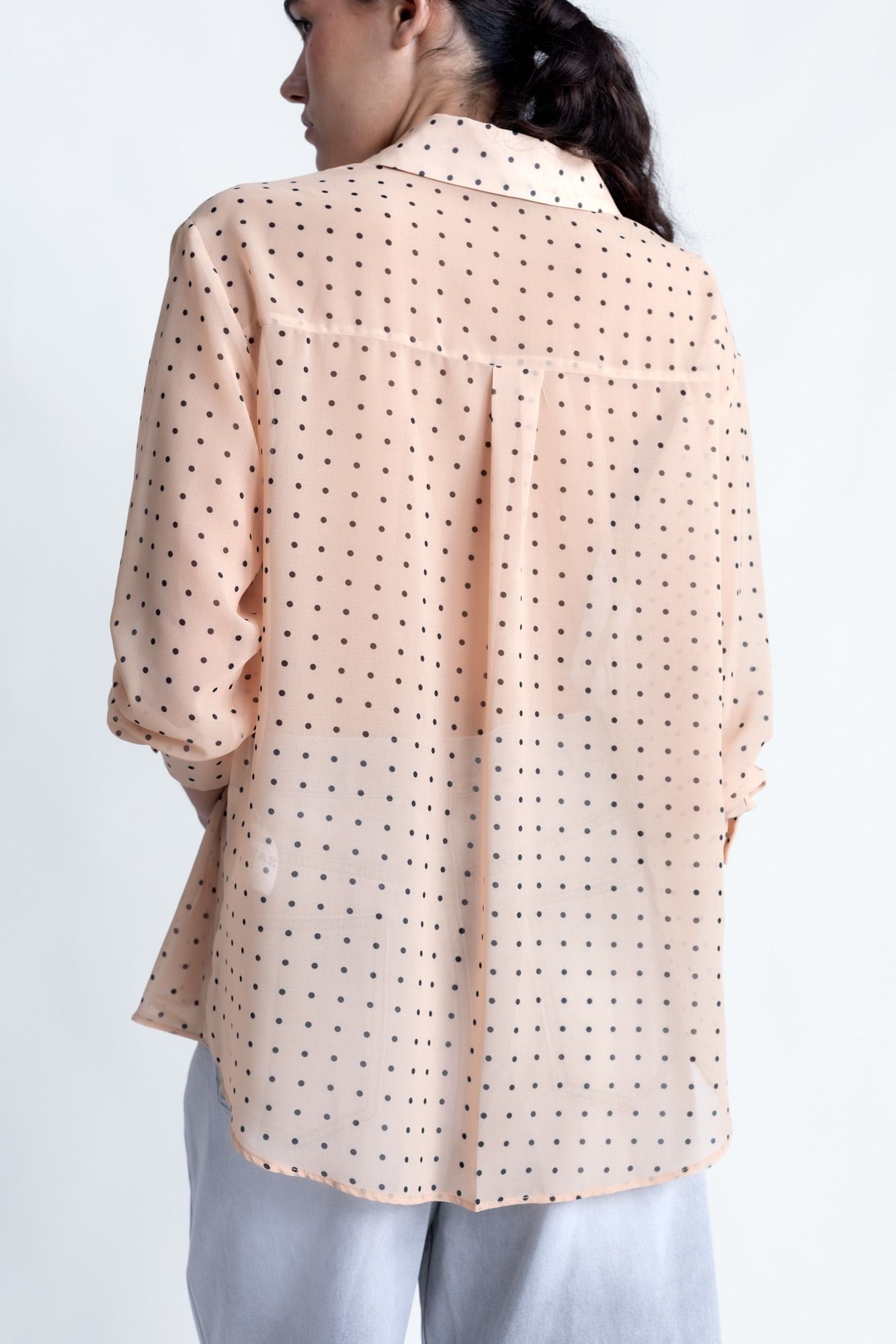 Blusa semitransparente para mujer en color beige con estampado clásico de lunares, botones frontales y mangas largas.