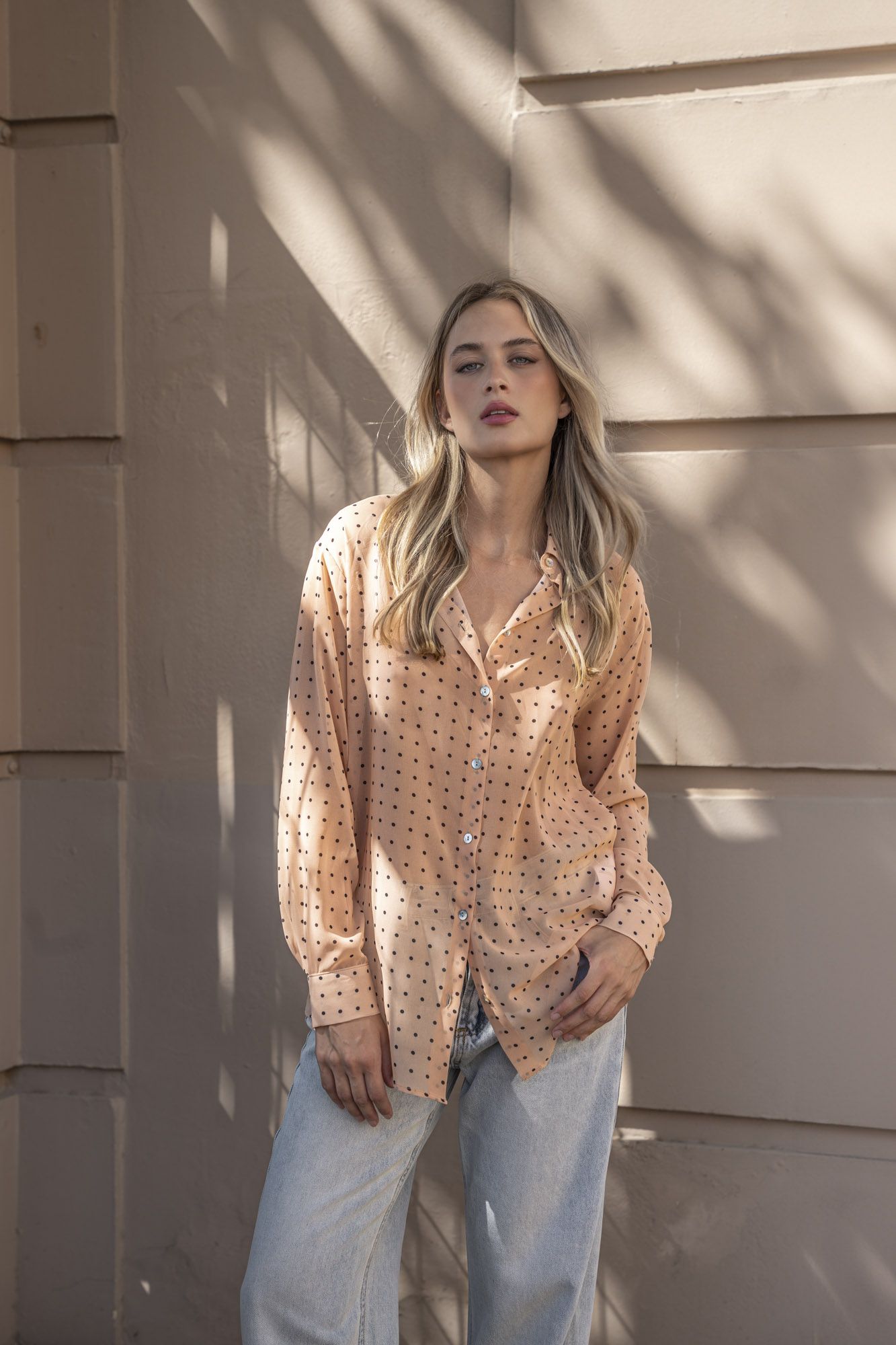 Blusa semitransparente para mujer en color beige con estampado clásico de lunares, botones frontales y mangas largas.