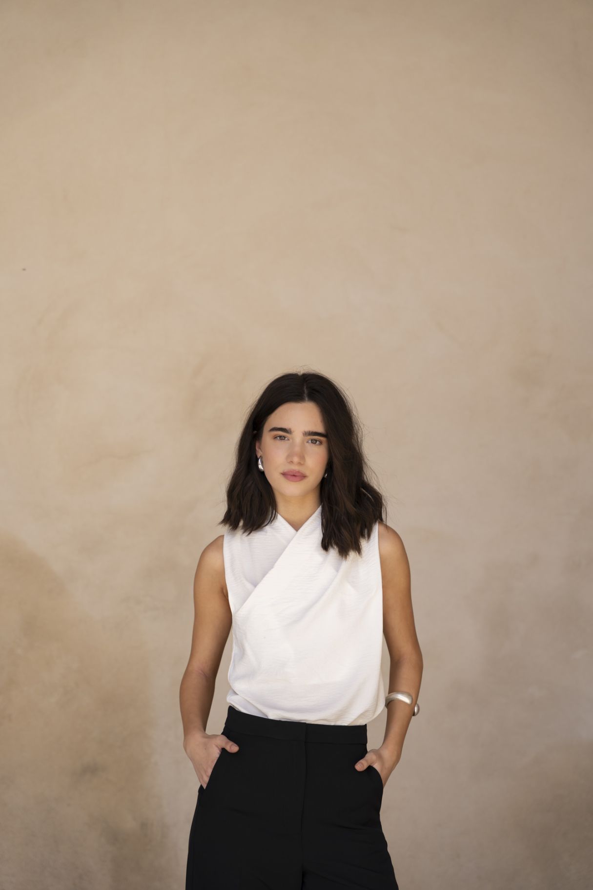 Blusa cruzada sin mangas para mujer en color crudo, con escote en V envolvente y silueta fluida satinada.