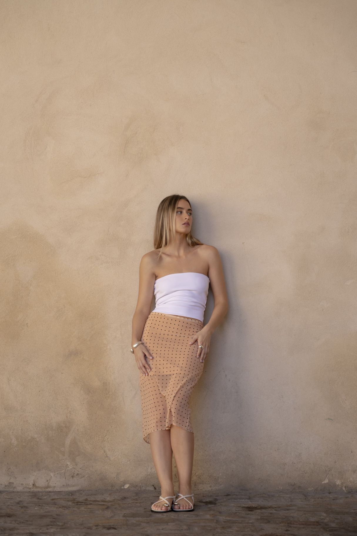 Falda midi de corte lápiz para mujer en color beige con estampado de lunares y abertura lateral para mayor movimiento.