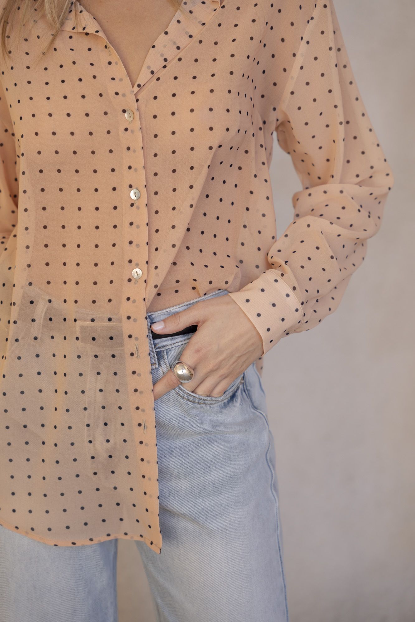 Blusa semitransparente para mujer en color beige con estampado clásico de lunares, botones frontales y mangas largas.