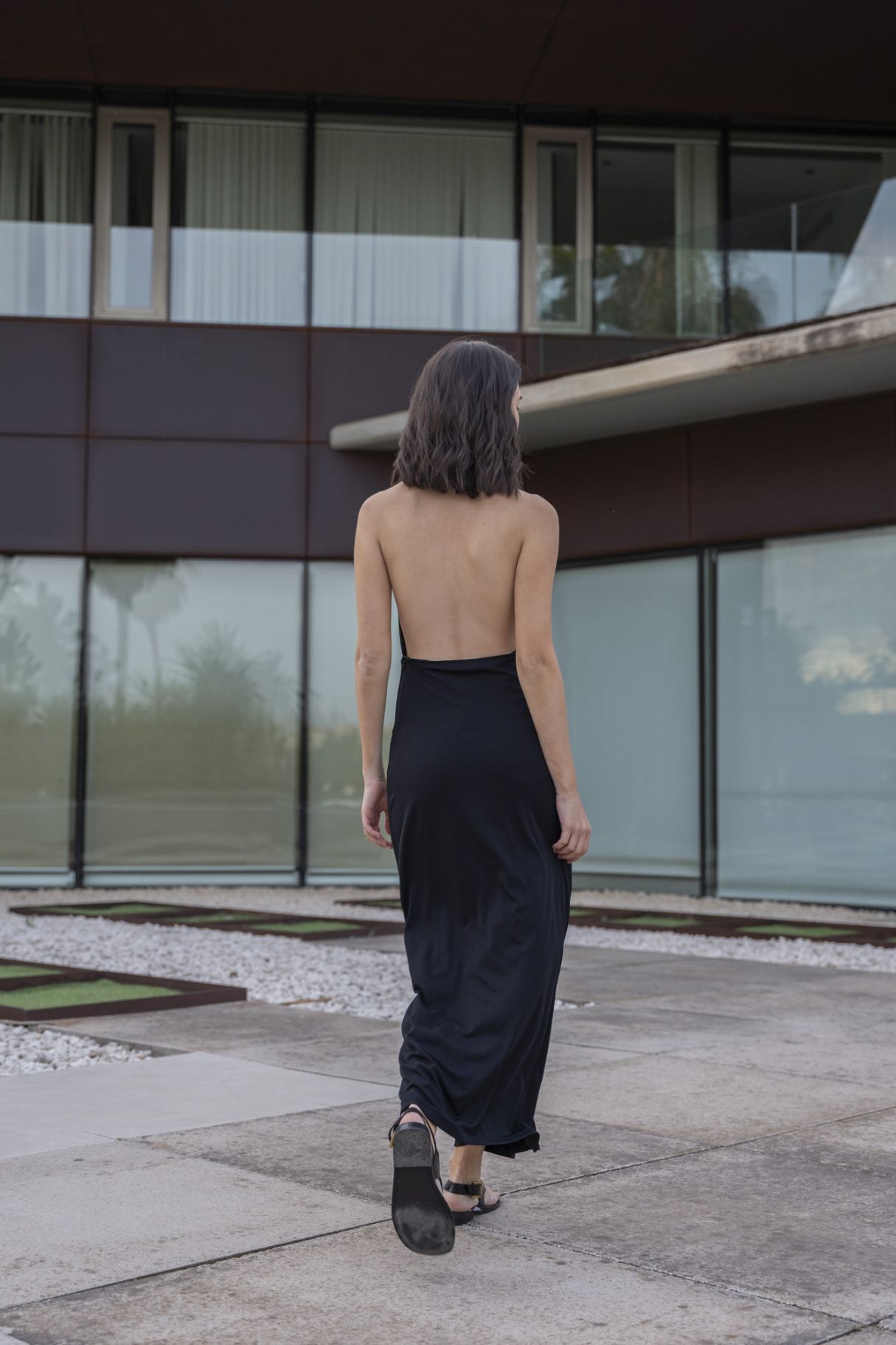Vestido midi ajustado para mujer en color negro con cuello tipo halter, hombros descubiertos y escote pronunciado en V.
