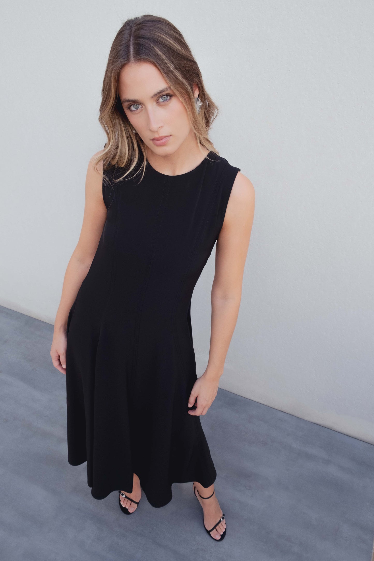 Vestido midi negro de corte minimalista con bajo de vuelo en nesgas
