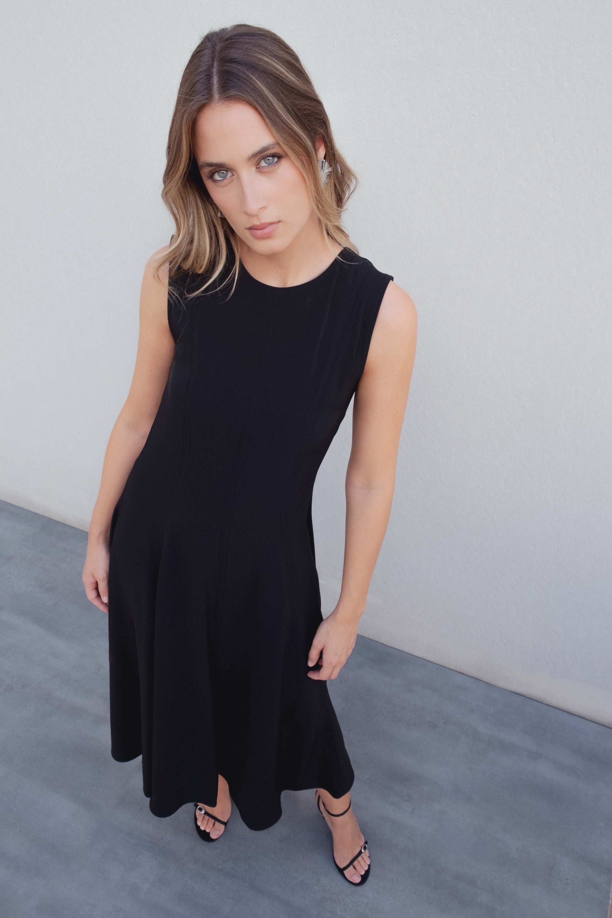Vestido midi negro de corte minimalista con bajo de vuelo en nesgas