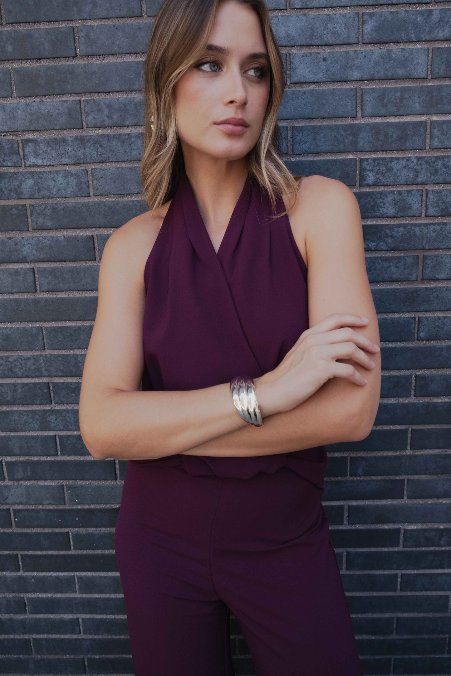 Mono de fiesta burdeos (rojo vino) con cuello halter y escote de pico. Detalle de nudo frontal y espalda descubierta. Pernera ancha.