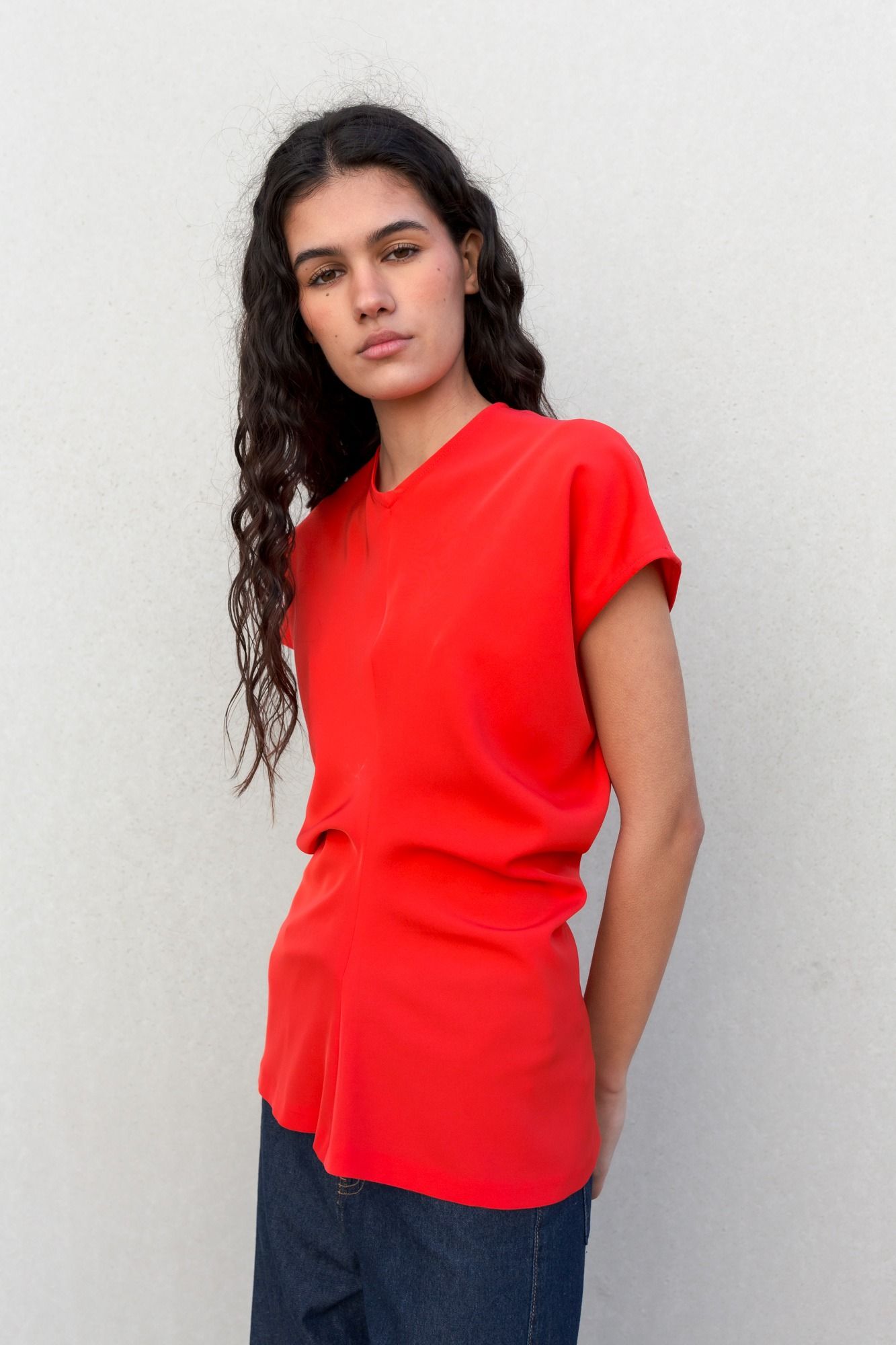 Blusa fluida para mujer en color rojo intenso con diseño texturizado de frunces frontales y mangas largas.