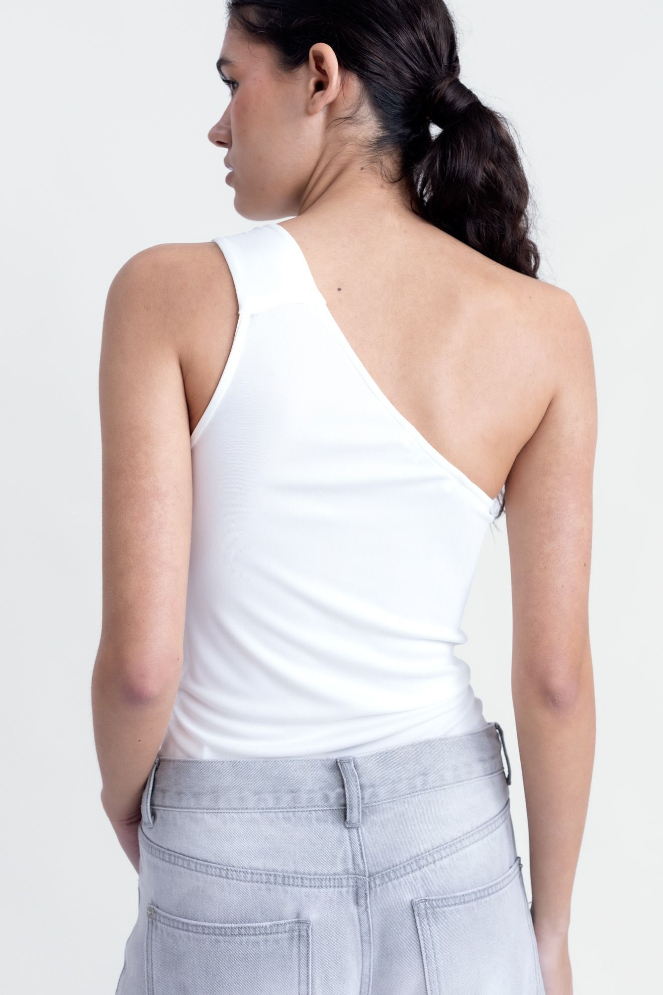 Top corto para mujer en color crudo con diseño asimétrico de un solo hombro y silueta ajustada de fiesta.