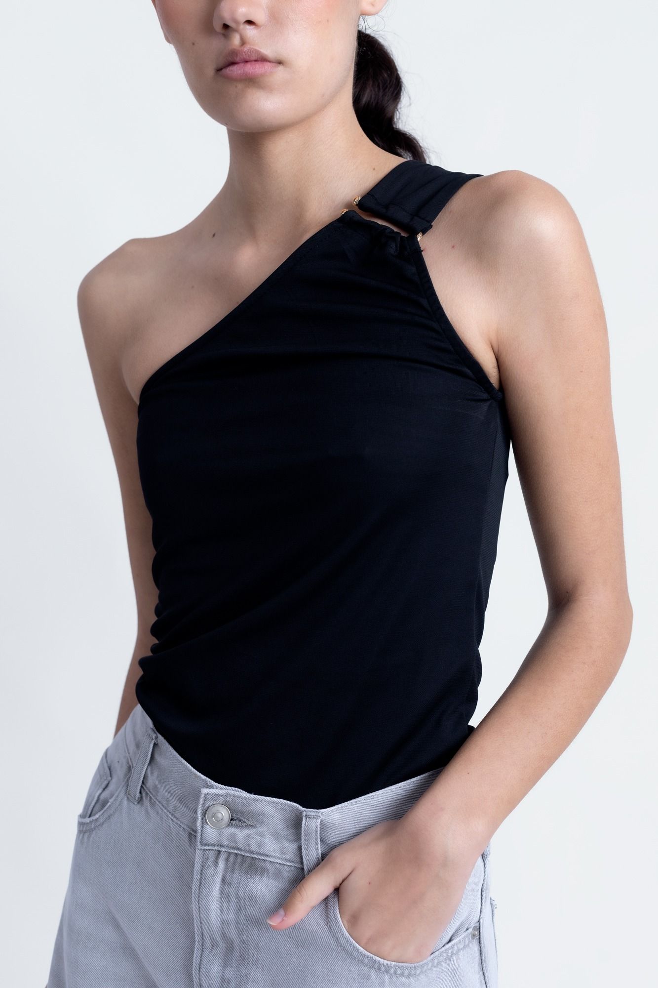 Top corto elástico para mujer en color negro con escote asimétrico de un solo hombro para looks de noche.