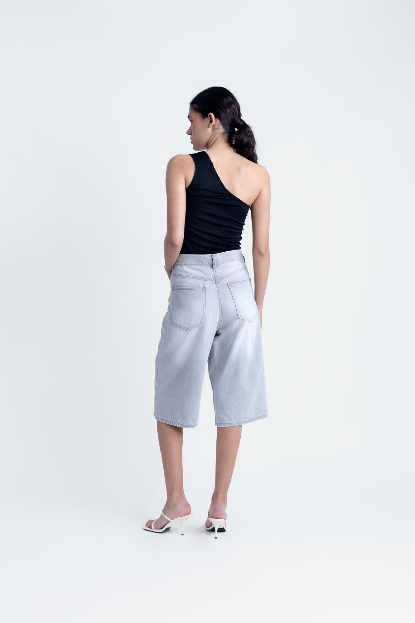 Top corto elástico para mujer en color negro con escote asimétrico de un solo hombro para looks de noche.